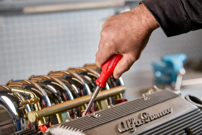 Mechanic using screwdriver on car engine